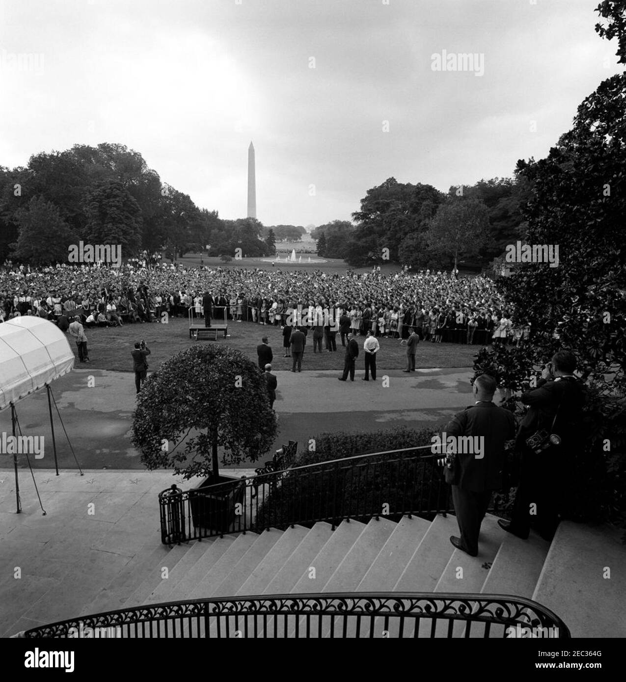 Visite des participants au séminaire de la Maison Blanche, 9 h 55. Le président John F. Kennedy (sur plateforme) prononce des discours d’adieu aux étudiants participant au séminaire d’été de la Maison Blanche. Également en photo : Oscar N. Smith, agent de la White House Communications Agency (WHCA); Abbie Rowe, photographe du National Park Service (NPS); Cleve Ryan, électricien du réseau de médias de la Maison Blanche; Helen Thomas, correspondante de la Maison Blanche pour United Press International (UPI); Sander Vanocur, correspondant de la Maison Blanche pour la National Broadcasting Company (NBC); Les agents des services secrets de la Maison Blanche, Bill Payne, Win Lawson et John Banque D'Images