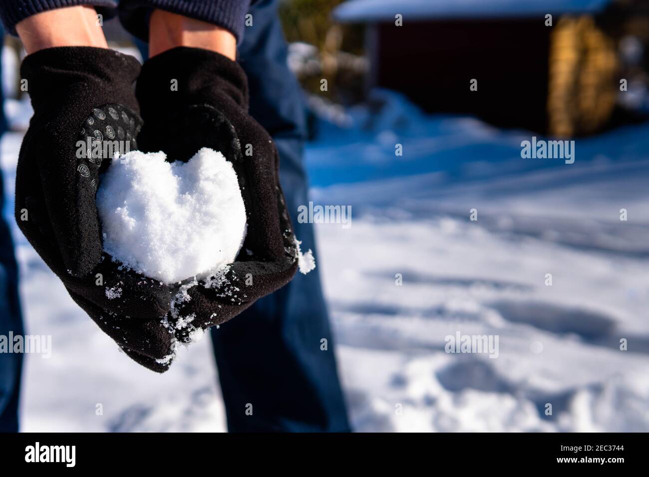 Tenir le cœur hors de la neige dans les mains pendant un hiver Jour Banque D'Images