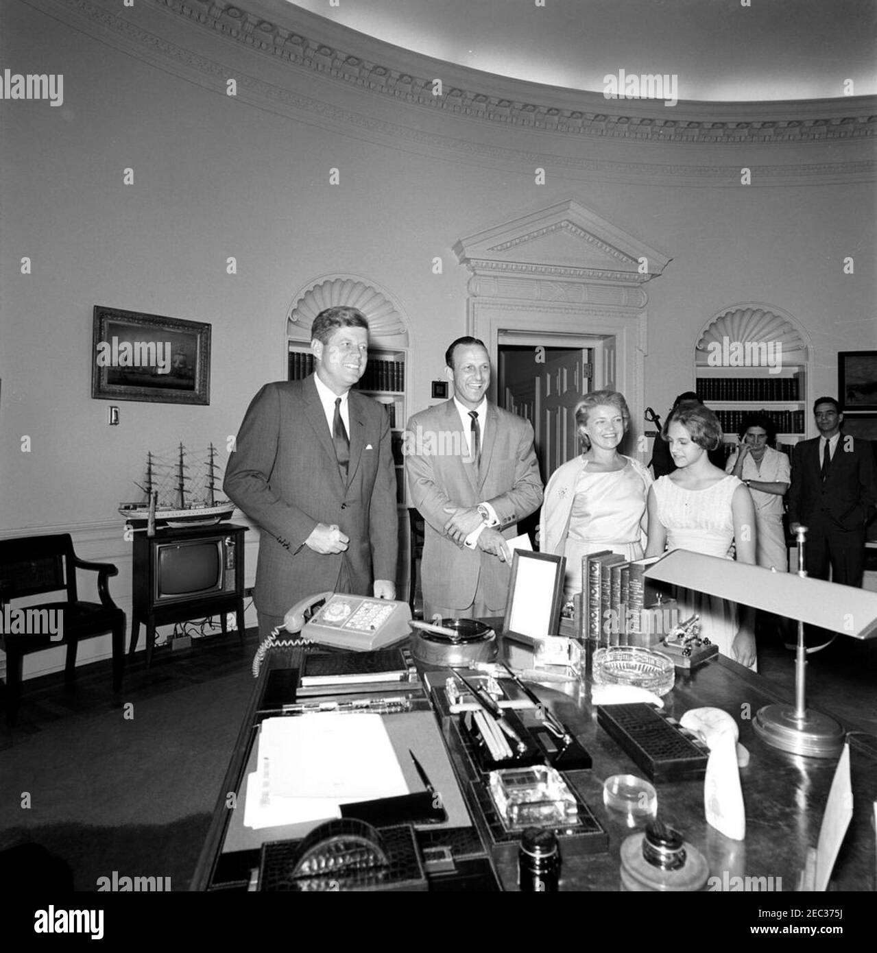 Visite de Stan Musial, joueur de la Ligue majeure de baseball (MLB) pour les Cardinals de Saint-Louis, et de la famille, 4:10. Le président John F. Kennedy visite Stan Musial, joueur de la Ligue majeure de baseball (MLB) pour les Cardinals de Saint-Louis, et sa famille. De gauche à droite : le président Kennedy; M. Musial; son épouse, Lillian Musial, et sa fille, Janet Musial. En arrière-plan (G-D): Agent du service secret de la Maison Blanche, Charlie Kunkel (pour la plupart caché); correspondant de la Maison Blanche pour United Press International (UPI), Helen Thomas; non identifié. Oval Office, Maison Blanche, Washington, D.C. Banque D'Images