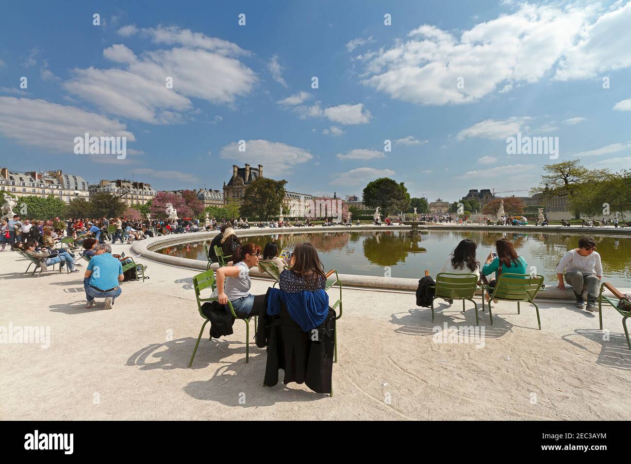 Jardin des Tuileries, Paris. Les touristes et les Parisiens se détendent sous le soleil de printemps autour d'une des piscines dans les jardins formels. Banque D'Images
