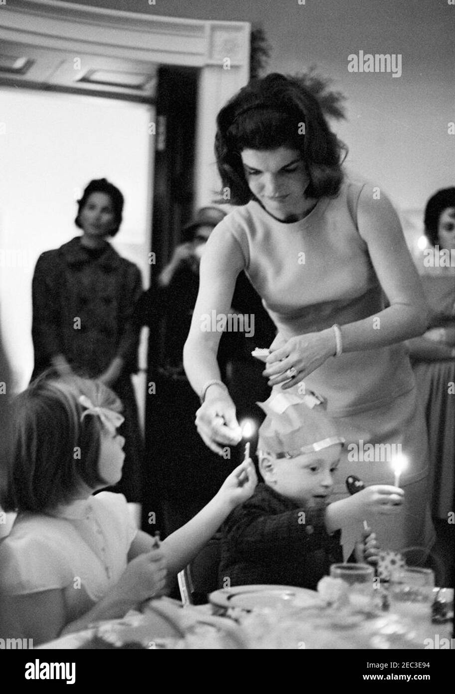 Fête d'anniversaire pour Caroline Kennedy et John F. Kennedy, Jr. La première dame Jacqueline Kennedy allume une bougie d'anniversaire pour sa fille, Caroline Kennedy, lors d'une fête conjointe pour Caroline et John F. Kennedy, Jr. Presidentu2019s Dining Room (Résidence), Maison Blanche, Washington, D.C. [les rayures sur l'image sont originales au négatif.] Banque D'Images
