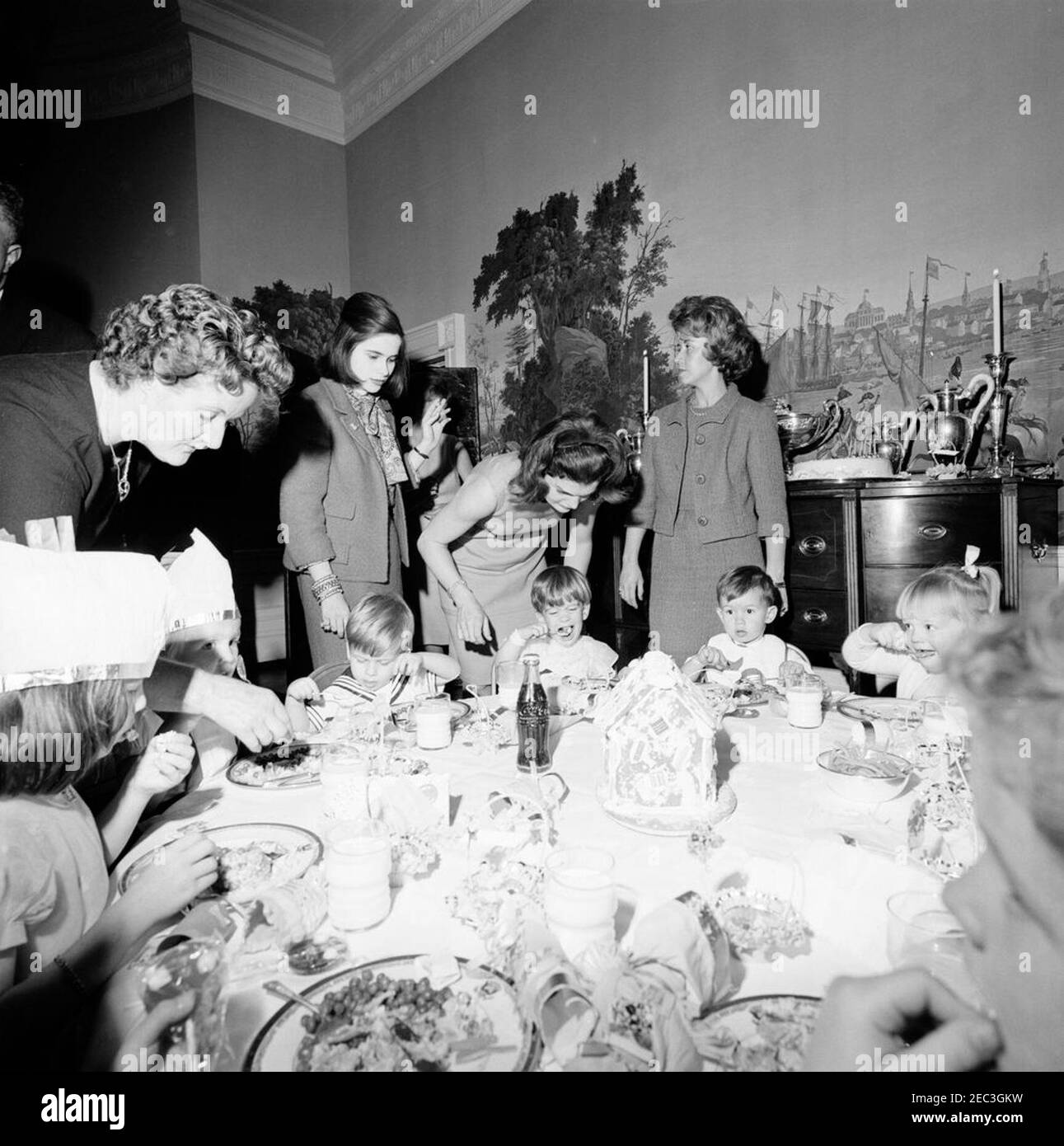 Fête d'anniversaire pour Caroline Kennedy et John F. Kennedy, Jr. John F. Kennedy, Jr. (Assis au centre), mange à une table dans la salle à manger du Presidentu2019s (résidence) de la Maison Blanche, Washington, D.C., lors d'une fête d'anniversaire conjointe pour lui et sa sœur, Caroline Kennedy; la première dame Jacqueline Kennedy se tient derrière son fils. Banque D'Images Fête d'anniversaire pour Caroline Kennedy et John F. Kennedy, Jr. John F. Kennedy, Jr. (Assis au centre), mange à une table dans la salle à manger du Presidentu2019s (résidence) de la Maison Blanche, Washington, D.C., lors d'une fête d'anniversaire conjointe pour lui et sa sœur, Caroline Kennedy; la première dame Jacqueline Kennedy se tient derrière son fils. Banque D'Images
