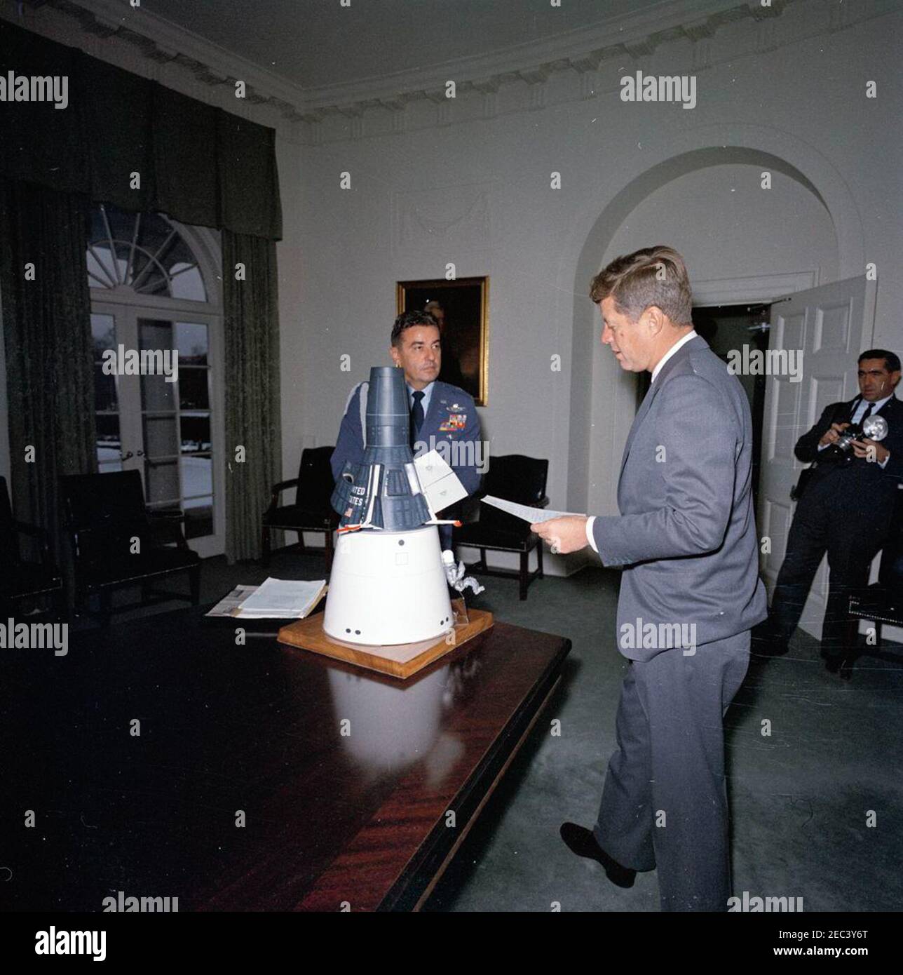 Le président Kennedy avec un modèle Gemini Capsule. Le Président John F. Kennedy voit un modèle à échelle d'une capsule Gemini dans la salle du Cabinet de la Maison Blanche, Washington, D.C.; Le modèle a été remis au Président Kennedy en cadeau de Noël par le personnel de McDonnell Aircraft Corporation, à la suite de la visite du Président du Conseil à l'usine McDonnellu2019s de St. Louis, le 12 septembre 1962. L'aide de la Force aérienne au président, le général de brigade Godfrey T. McHugh, est à gauche; le photographe de la Maison Blanche, le chef Robert L. Knudsen, est à droite. [Voir aussi Mo 63.1922a-c, u0022Modèle de la Spacecra Gemini Banque D'Images