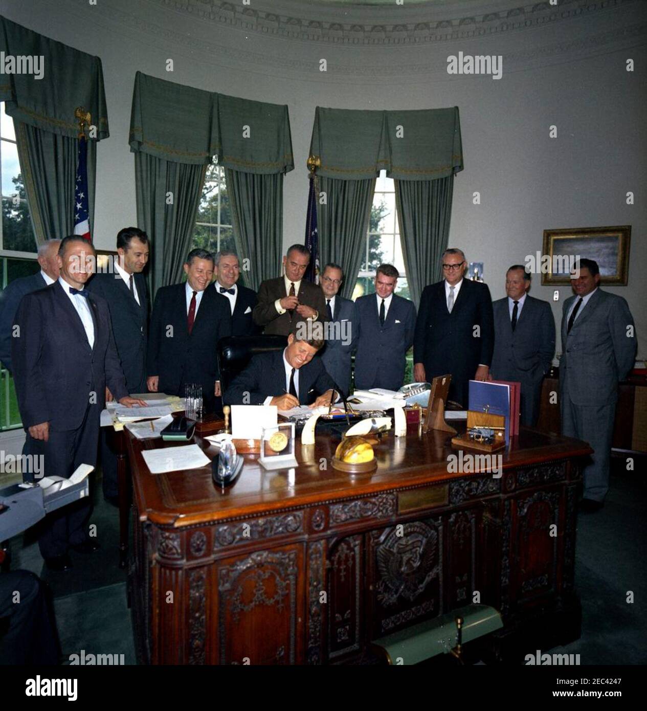 Signature de facture - Padre Island National Seashore, 12:30. Le président John F. Kennedy (assis à son bureau) signe un projet de loi visant à établir le Padre Island National Seashore au Texas. Debout (G-D): Sénateur Frank E. Moss (Utah); non identifié (à l'arrière, surtout caché); Représentant J. T. Rutherford, sénateur Ralph W. Yarborough, et Représentant John Young, tous du Texas; Vice-président Lyndon B. Johnson; sénateur Alan Bible (Nevada); non identifié; Représentant John Kyl (Iowa); non identifié; Représentant Joe M. Kilgore (Texas). Les personnes non identifiées peuvent inclure: Le juge Oscar Dancy, du comté de Cameron, Texa Banque D'Images