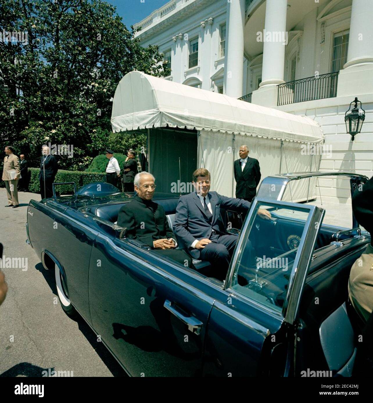 Défilé en l'honneur du Dr Sarvepalli Radhakrishnan, Président de l'Inde, 12 h 35. Le Président John F. Kennedy et le Président de l'Inde, M. Sarvepalli Radhakrishnan, s'assoient à l'arrière de la limousine présidentielle (Lincoln-Mercury Continental convertible) avant une parade en l'honneur du Président Radhakrishnan. En arrière-plan (G-D) : aide militaire au président Kennedy, le général Chester V. Clifton; non identifié; le chef adjoint du protocole des États-Unis, William J. Tonesk; un officier de police de la Maison-Blanche non identifié; un adjoint spécial au président Kennedy, John J. McNally; un membre non identifié du personnel de la Maison-Blanche. S Banque D'Images