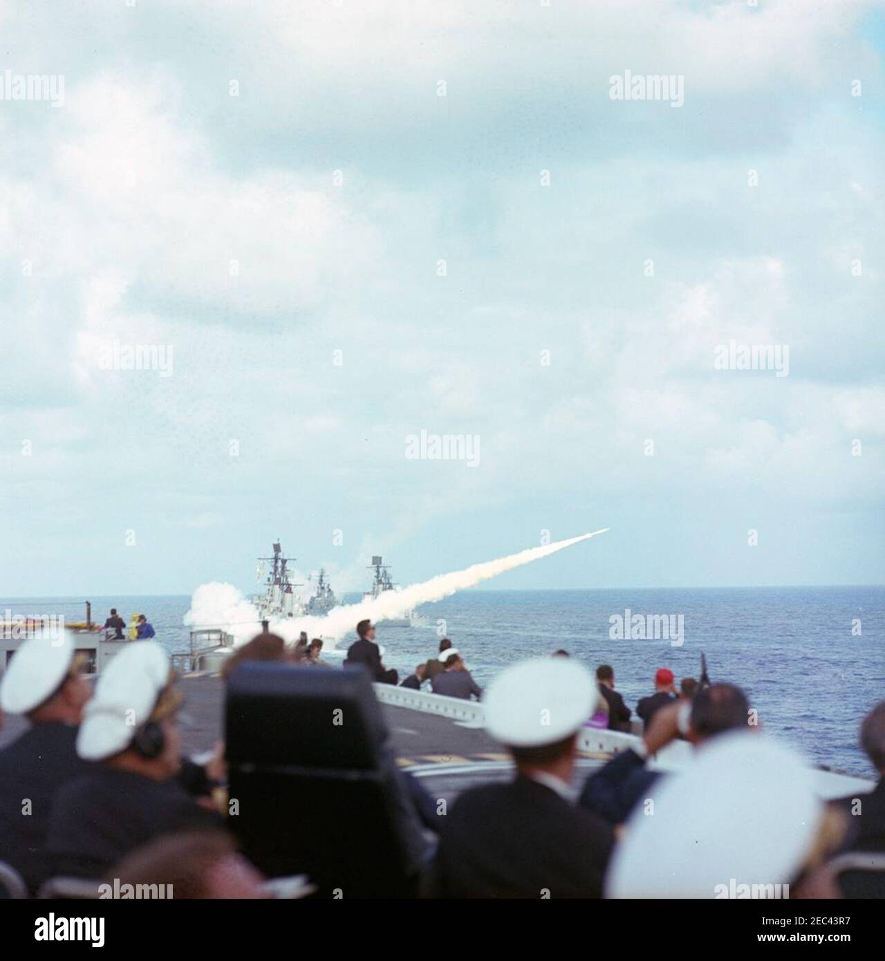 Voyage aux États de l'Ouest : visite de la flotte du Pacifique, le président Kennedy à bord de l'USS Kitty Hawk, 5:00. Le président John F. Kennedy (assis sur la chaise à dossier haut à gauche) et d'autres invités distingués regardent des démonstrations guidées de missiles depuis le pont de vol du porte-avions USS Kitty Hawk (CVA-63), lors d'une visite à la flotte du Pacifique des États-Unis au large de la côte de San Diego, en Californie. Banque D'Images