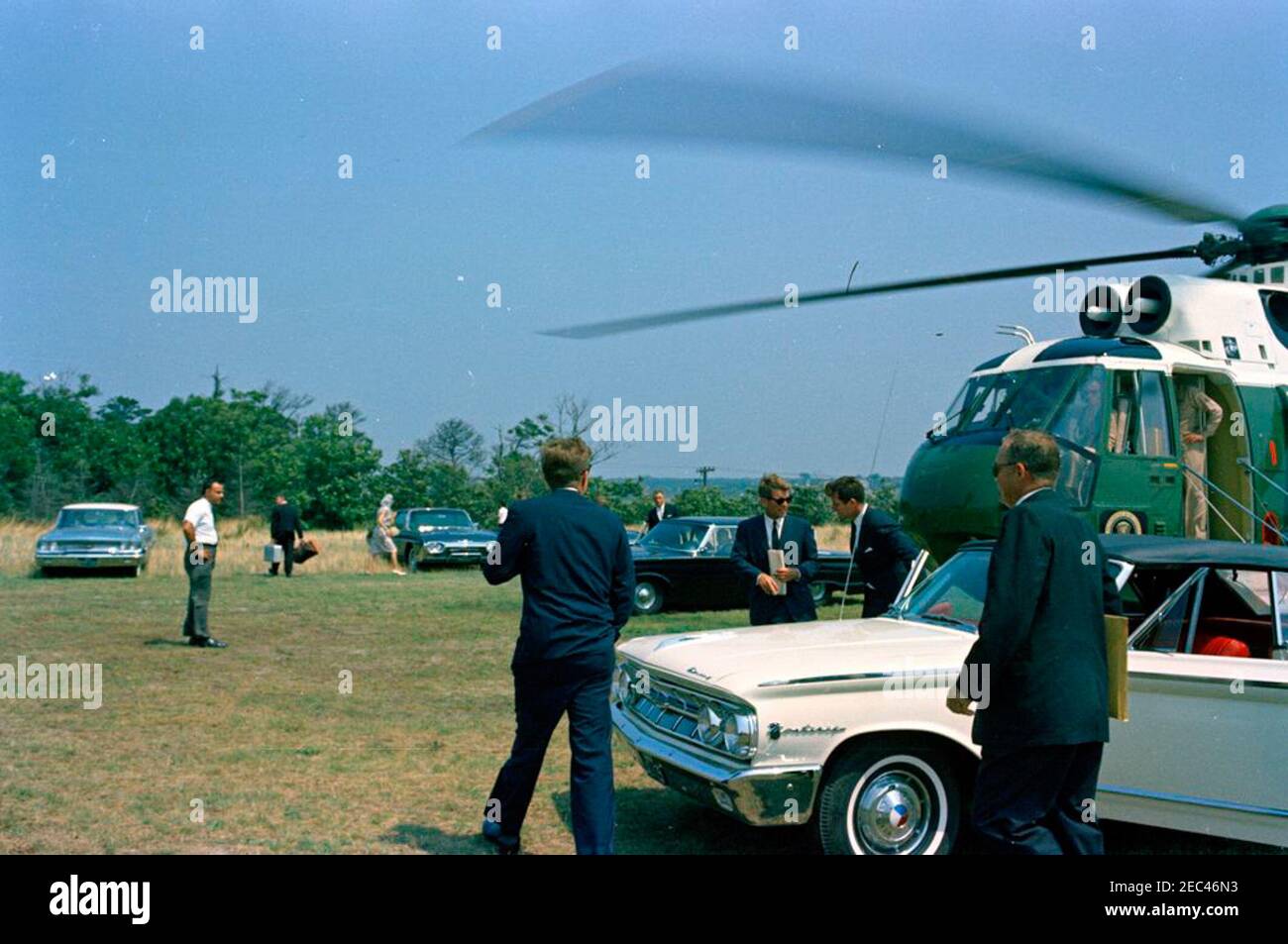 Voyage au port de Hyannis : président Kennedy avec Robert F. Kennedy (RFK) u0026 Edward M. Kennedy (EMK) à l'hôpital de la base aérienne d'Otis. Le président John F. Kennedy (au centre, à l'arrière), le procureur général Robert F. Kennedy (debout derrière la voiture, portant des lunettes de soleil) et le sénateur Edward M. Kennedy du Massachusetts (à droite du procureur général) arrivent à la base aérienne d'Otis; Le président Kennedy et ses frères se sont rendus à l'hôpital de la base aérienne d'Otis après le décès du nouveau-né Patrick Bouvier Kennedy, le président et la première dame Jacqueline Kennedyu2019s. Également représenté : agents de service secret, Banque D'Images