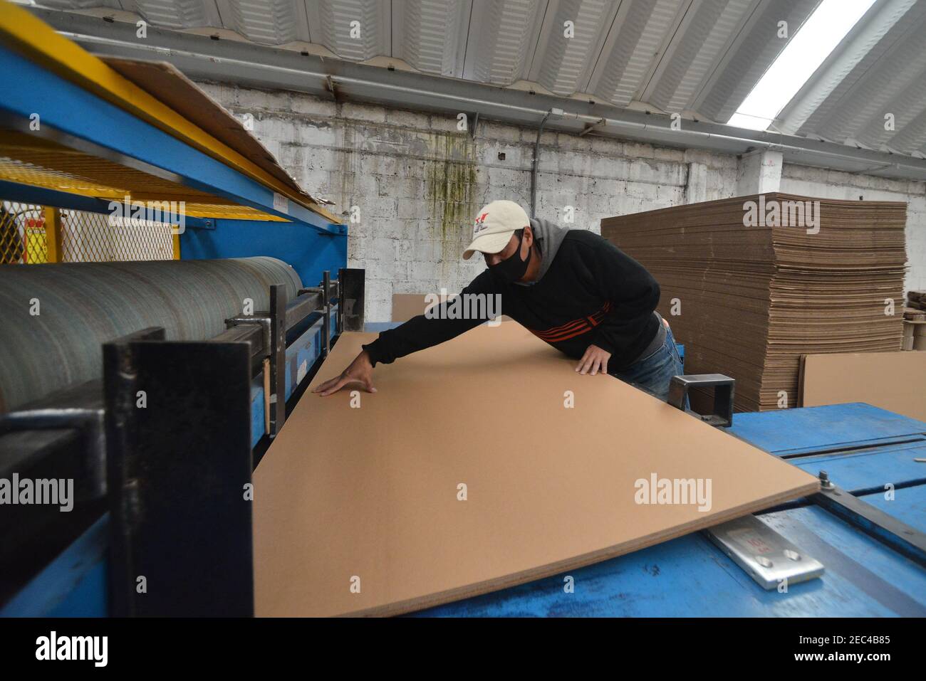 Toluca, Mexique. 12 février 2021. Un travailleur de l'usine de boîtes en carton KJ, pendant l'assemblage d'un cercueil en carton. En raison de l'augmentation des décès de covid et de l'augmentation du chômage dans le pays, l'usine de carton KJ met en œuvre des coffrets fabriqués en carton recyclé, aux personnes à faible revenu et qui n'ont pas le soutien d'acheter un cercueil en bois ou en aluminium. Ces cercueils en carton sont principalement destinés aux travailleurs d'entreprises ou aux salons funéraires. (Photo par Eyepix Group/Pacific Press) crédit: Pacific Press Media production Corp./Alay Live News Banque D'Images