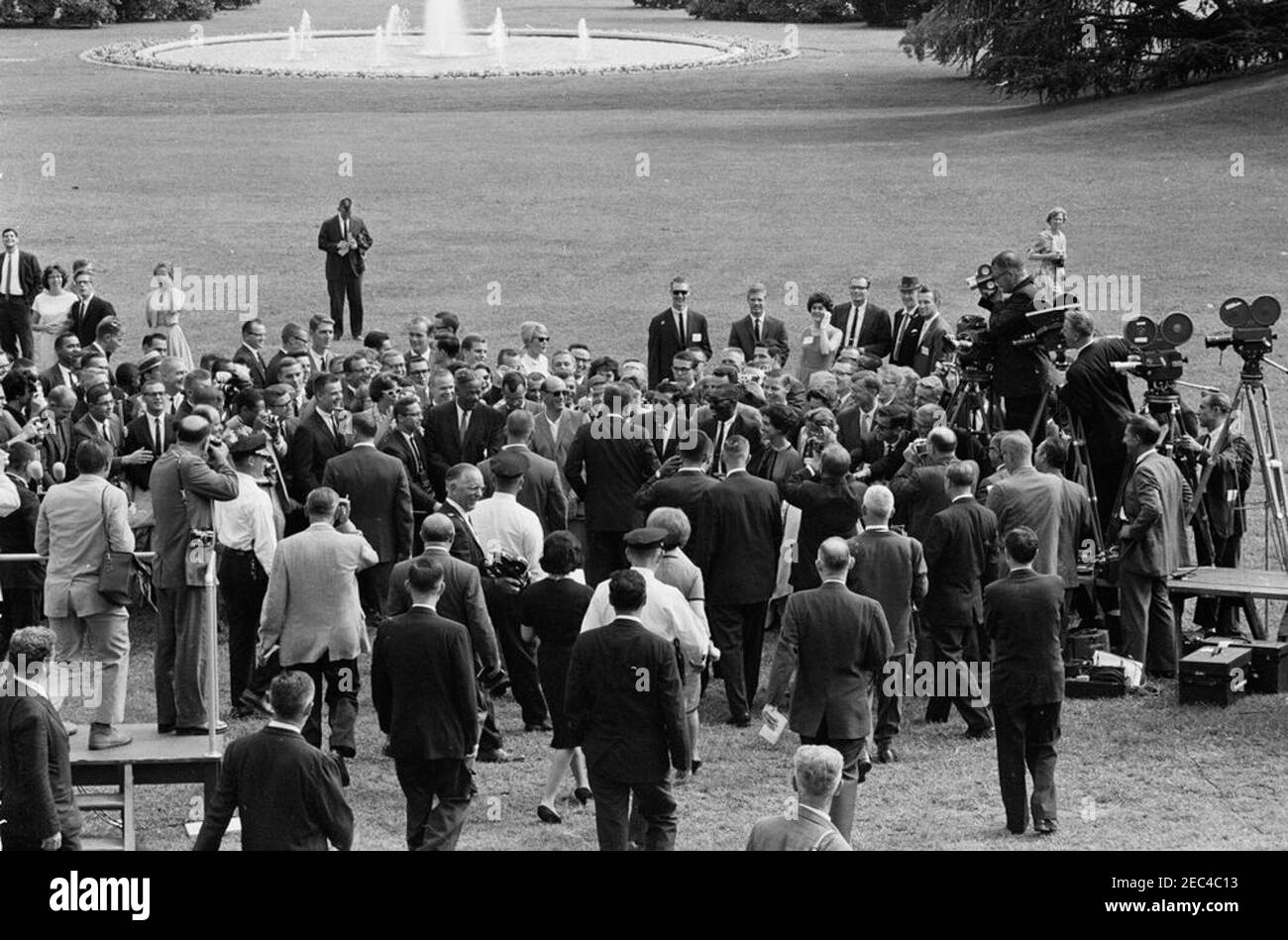 Visite des stagiaires du corps de la paix, 4:25. Le Président John F. Kennedy (au centre, à huis clos) visite un groupe de stagiaires du corps de la paix. Également en photo : Abbie Rowe, photographe du National Park Service (NPS); photographe de presse pour United Press Movietone, Thomas J. Craven, Sr.; électricien du réseau de médias de la Maison Blanche, Cleve Ryan. South Lawn, Maison Blanche, Washington, D.C. Banque D'Images