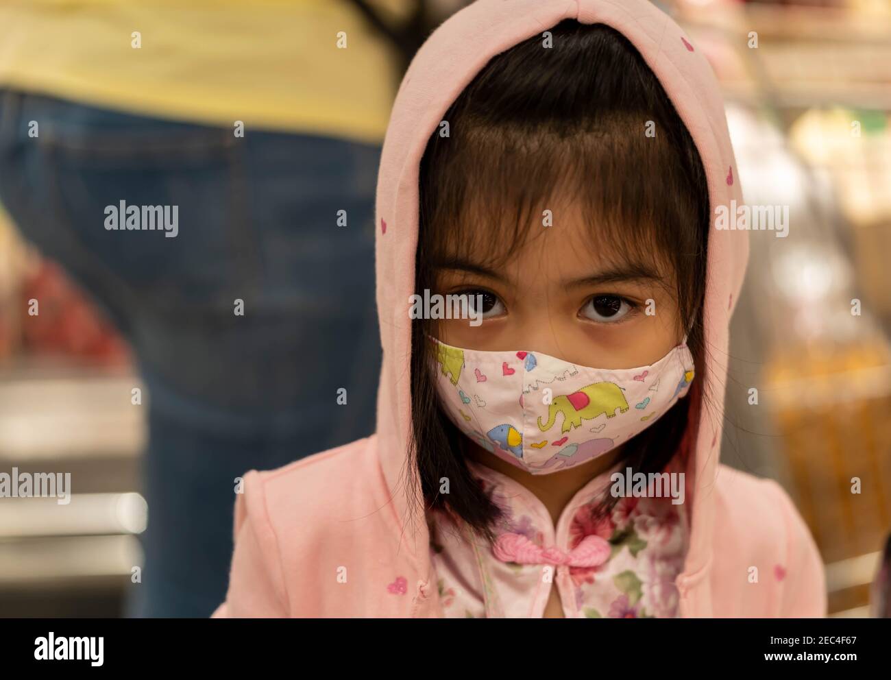 Petite fille avec masque de tissu se protéger contre le coronavirus quand l'enfant va au supermarché. Petite fille asiatique portant un masque dans un marché Banque D'Images