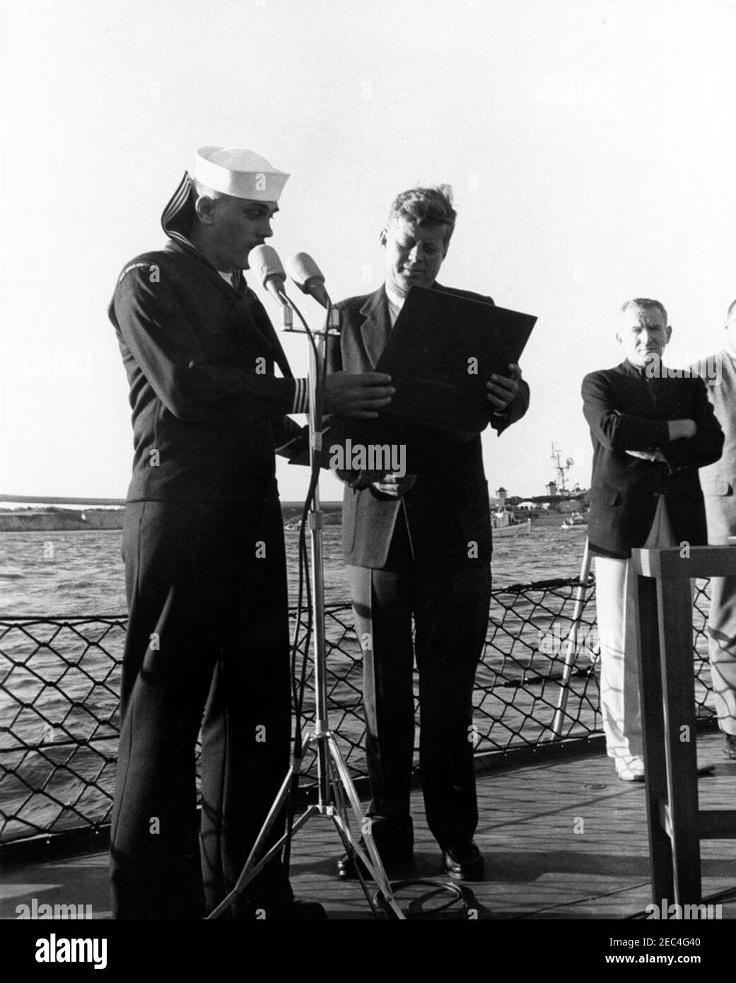 Le Président Kennedy Watches la 1ère course de la coupe Americau0027s. Le président John F. Kennedy reçoit un modèle de navire de destroyer, USS Joseph P. Kennedy, Jr. (Non représenté), comme cadeau de l'équipage du Joseph P. Kennedy, Jr., tout en assistant à la première course de la coupe Americau0027s 1962 à bord du destroyer. Sous-secrétaire de la Marine, Paul u0022Redu0022 Fay, se trouve à droite. Newport, Rhode Island. Banque D'Images