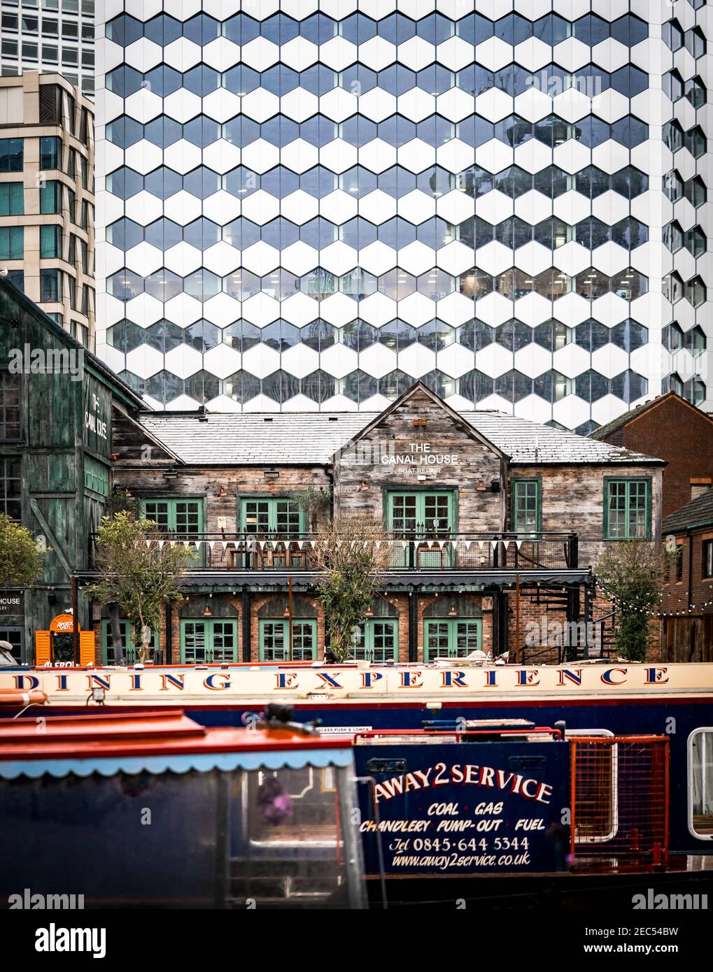 Birmingham Canal House Bar Restaurant, Wharfside pub en bois sur la rivière avec barges et bateaux étroits amarrés en face et bâtiments modernes du quartier financier Banque D'Images