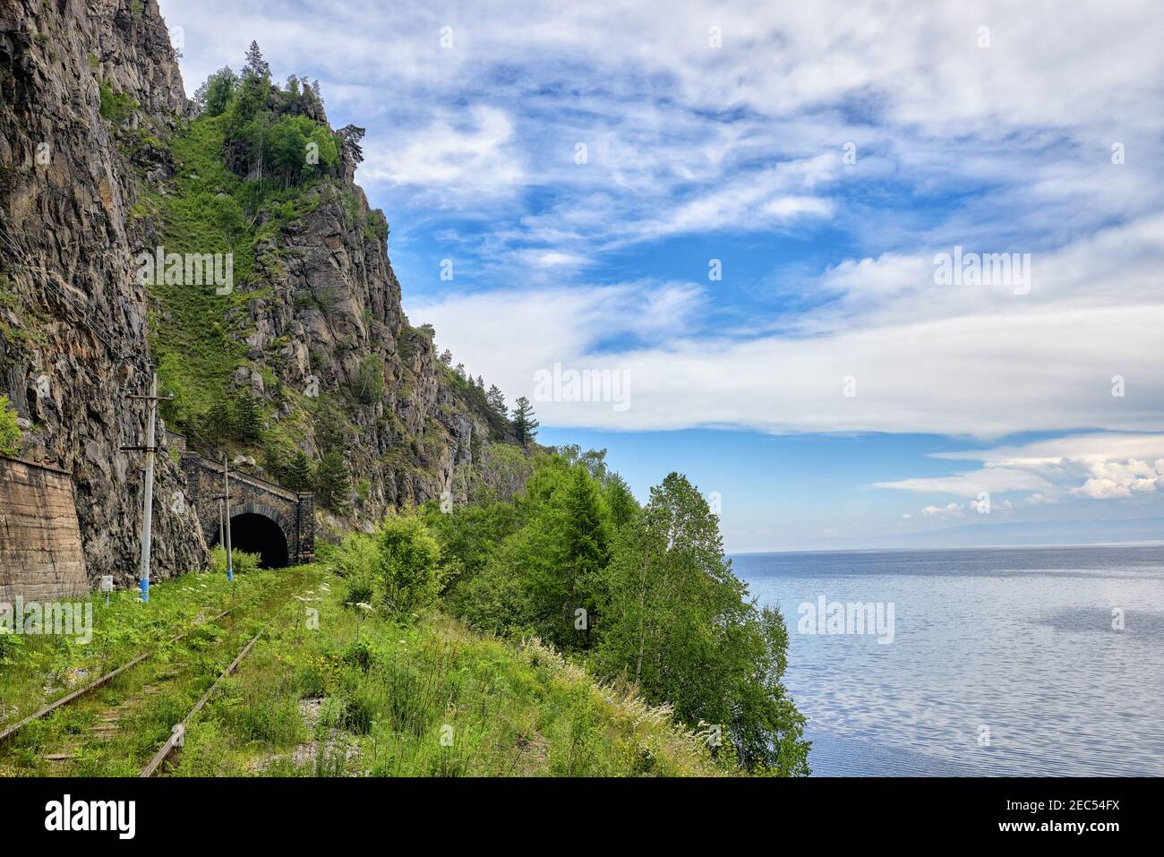 Un vieux chemin de fer au bord du lac Baikal. Le portail du tunnel sous la haute falaise. Le chemin est surcultivé avec de l'herbe verte. Région d'Irkoutsk. Est Banque D'Images