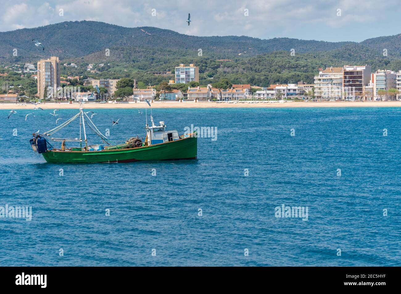 Bateau de pêche au chalutier suivi par des mouettes et des goélands revenant au port, arrière-plan littoral de la Costa Brava panorama Banque D'Images