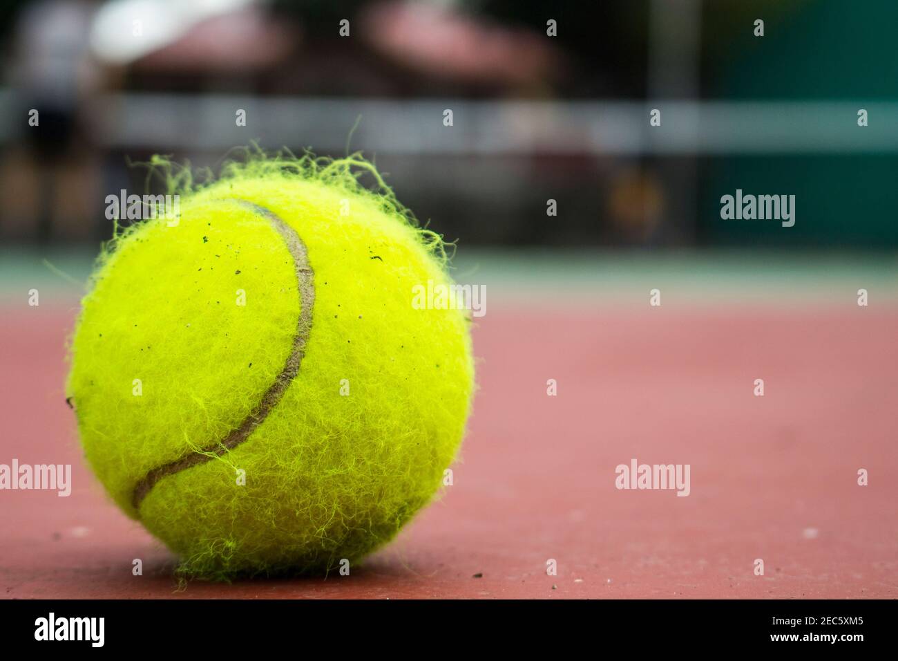 Ballon de tennis jaune sur le court rouge. Photo de la balle de tennis en  feutre. Concept de sports d'extérieur d'été. Jeu de tennis. Filet de tennis  et joueur sur la ba