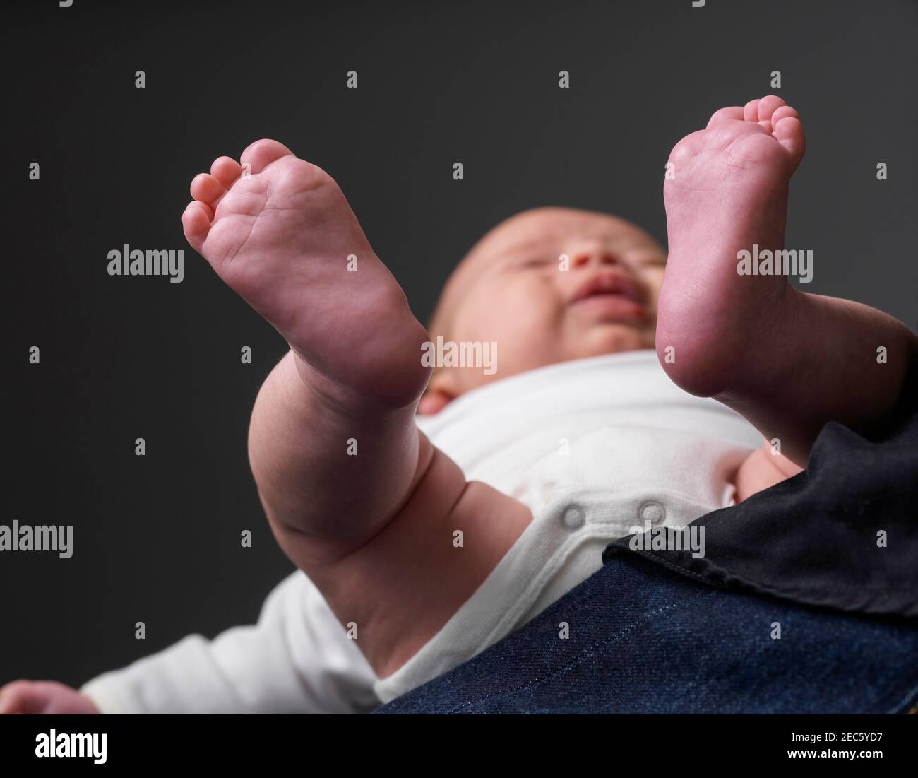 bébé allongé sur la plante des genoux du père visible Banque D'Images