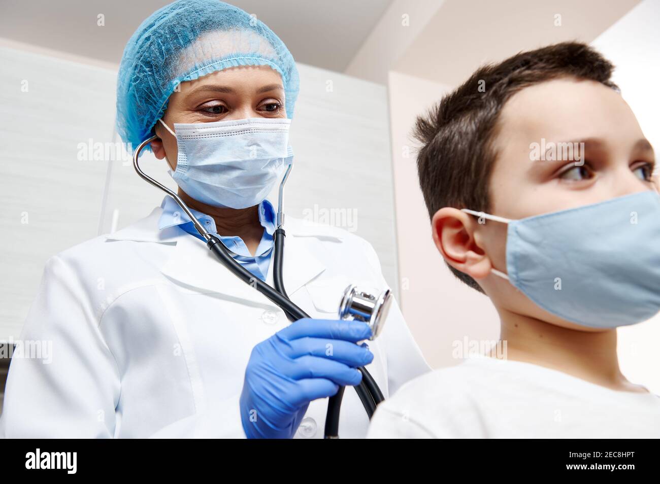 Pédiatre féminin tenant un stéthoscope et auscultant un petit patient. Examen préventif du pédiatre Banque D'Images