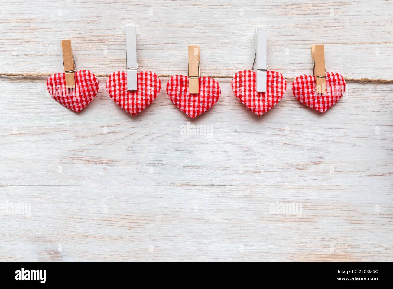 Coussin cousu coeur à carreaux rouges bordure de rangée sur des épingles à linge aux planches de bois blanc peint rustique. L'histoire de la Saint-Valentin. Concept de la journée des amoureux heureux. Co Banque D'Images