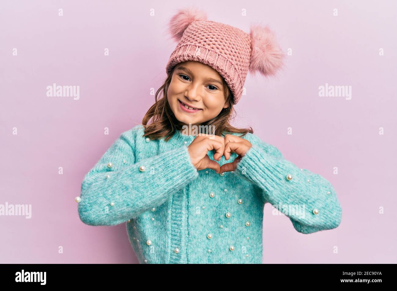 Petite belle fille portant un pull en laine et un joli chapeau d'hiver  souriant dans l'amour faisant le symbole de coeur forme avec les mains.  Concept romantique Photo Stock - Alamy