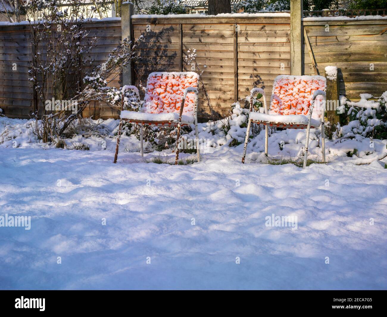 deux chaises orange dans un jardin recouvert de neige une journée d'hiver ensoleillée Banque D'Images