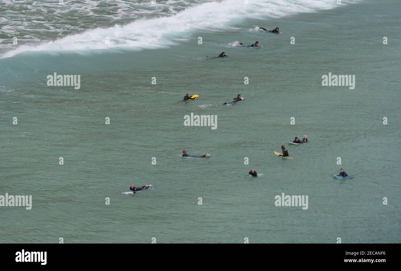 Surfeurs attendant une vague au large de la plage de Porthcurno, Penwith Peninsula, Cornouailles Banque D'Images