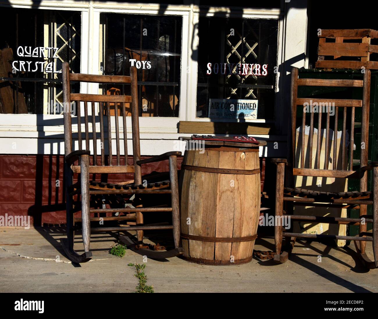 Le canon en bois sert de table pour un jeu de dames devant un magasin de l'ancien pays. Deux rockers rustiques en bois se trouvent à côté d'une table et d'une table de jeux. Banque D'Images