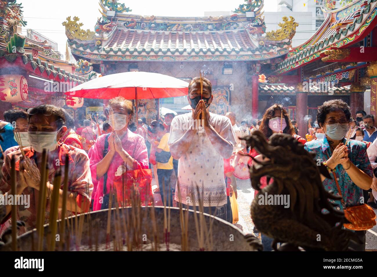 Les adorateurs en masques faciaux prient à une pagode à Bangkok pendant Nouvel an chinois Banque D'Images