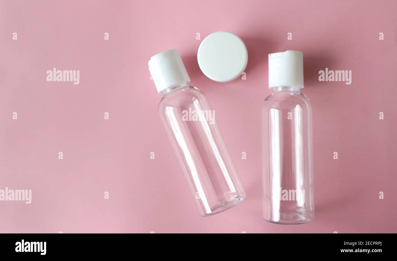 Flacons cosmétiques transparents en plastique avec couvercle blanc sur un fond rose Banque D'Images