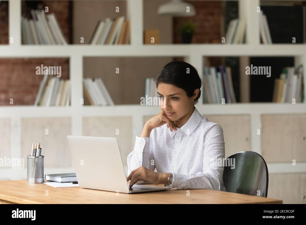 Une femme indienne pensive travaille sur un ordinateur portable Banque D'Images
