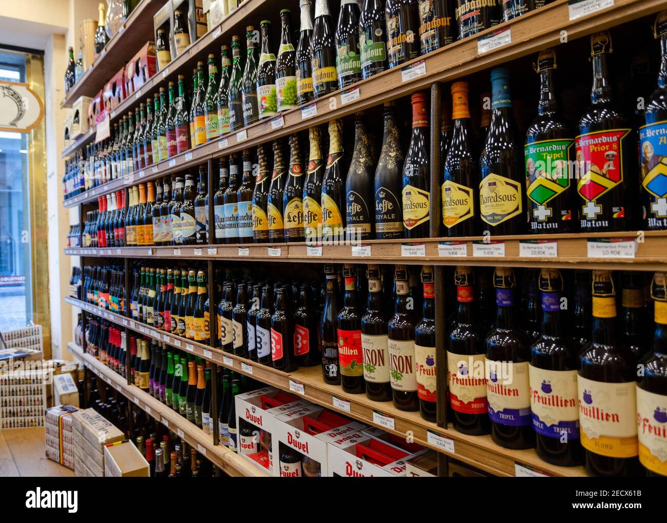 Variété de bières artisanales belges en vente dans un magasin, bouteilles de marque en vitrine