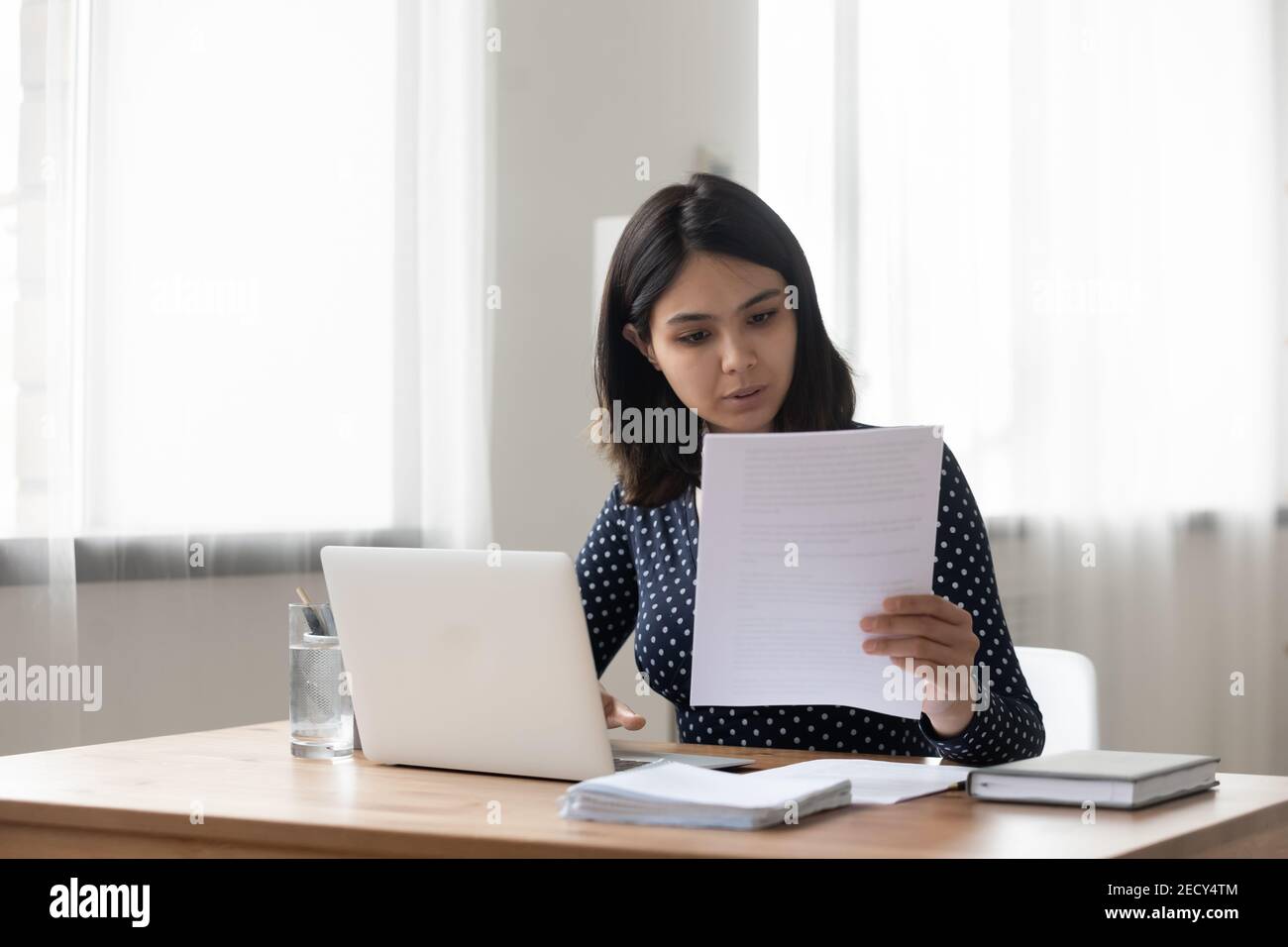 Femme asiatique du millénaire attentive tenant un document papier de lettre Banque D'Images