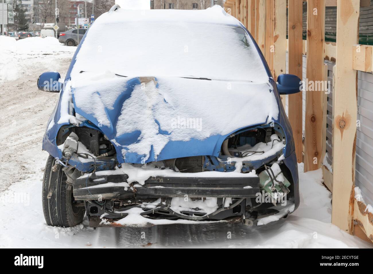la voiture bleue s'est écrasée sans phares ni pare-chocs après un accident garé par la route sous une couche de neige une journée d'hiver froide Banque D'Images