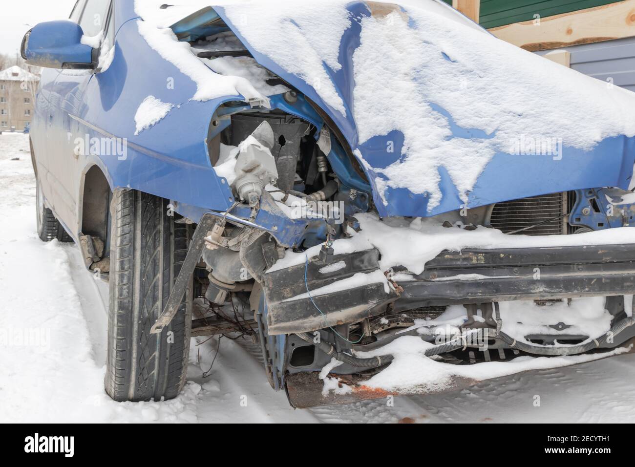 la voiture bleue s'est écrasée sans phares ni pare-chocs après un accident garé par la route sous une couche de neige une journée d'hiver froide Banque D'Images