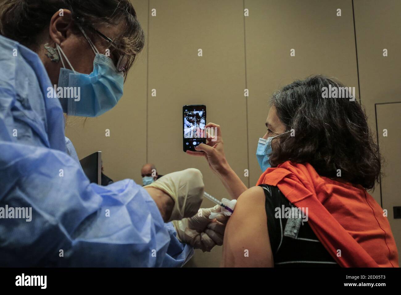 Beyrouth, Liban. 14 février 2021. Une femme prend un selfie alors qu'elle reçoit une dose du vaccin Pfizer/BioNTech coronavirus (COVID-19) au centre médical de l'Université américaine après que le Liban ait reçu hier, samedi, le premier lot de vaccins. Credit: Marwan Naamani/dpa/Alamy Live News Banque D'Images
