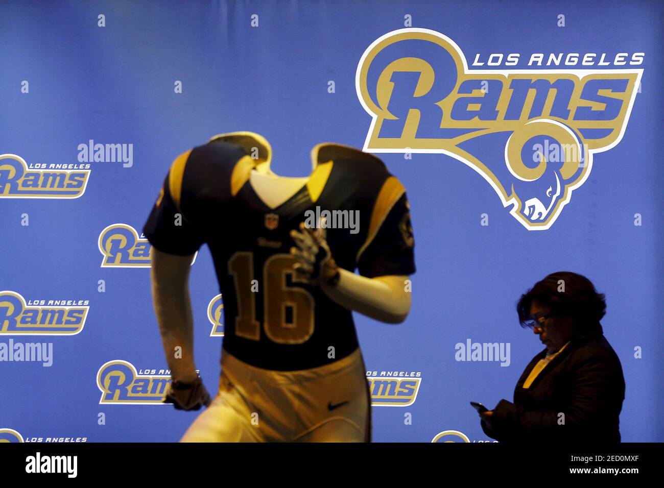 Une femme regarde son téléphone alors qu'elle passe devant un mannequin Los Angeles Rams à l'expérience NFL, une attraction Super Bowl 50, à San Francisco, en Californie, le 5 février 2016. REUTERS/Mike Blake photo fournie par action Images Banque D'Images
