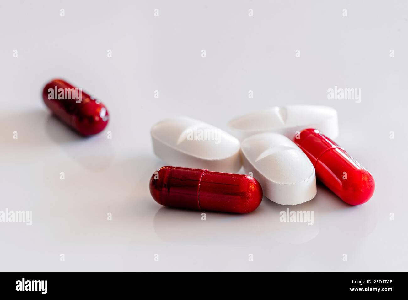 Assortiment de pilules et capsules colorées et blanches placées sur blanc tableau Banque D'Images