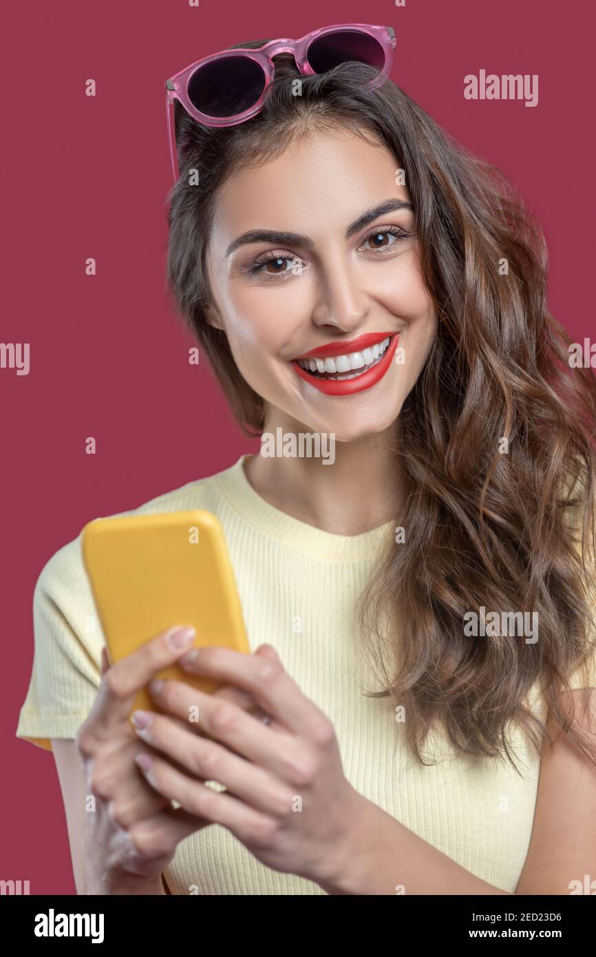 Gros plan d'une belle femme heureuse avec un smartphone jaune Banque D'Images