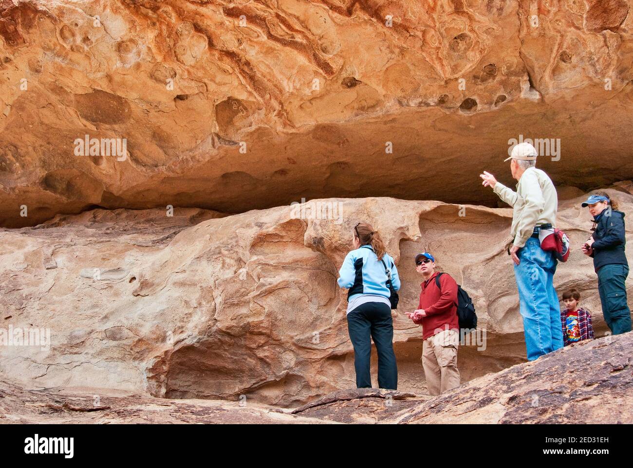 Bob White, guide de visite volontaire, visiteurs dans une grotte avec masques, pictogrammes dessinés par les peuples Jornada Mogollon, parc national Hueco Tanks, Texas, Etats-Unis Banque D'Images