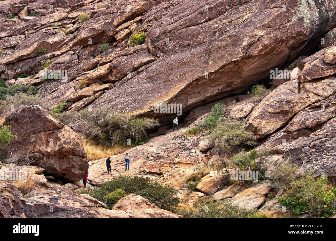 Visiteurs dans une grotte avec des pictogrammes de masques, dessinés par les peuples Jornada Mogollon, le parc national et site historique de Hueco Tanks, près d'El Paso, Texas, Etats-Unis Banque D'Images