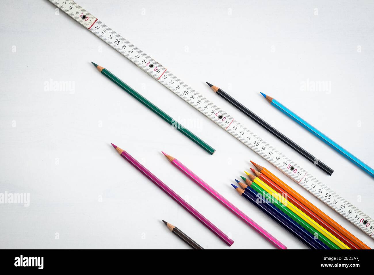 Fond blanc pour la nouvelle année scolaire 2020, des crayons de couleur et un mètre en bois pour respecter la distance de sécurité dans la salle de classe contre le Covid 19 Banque D'Images