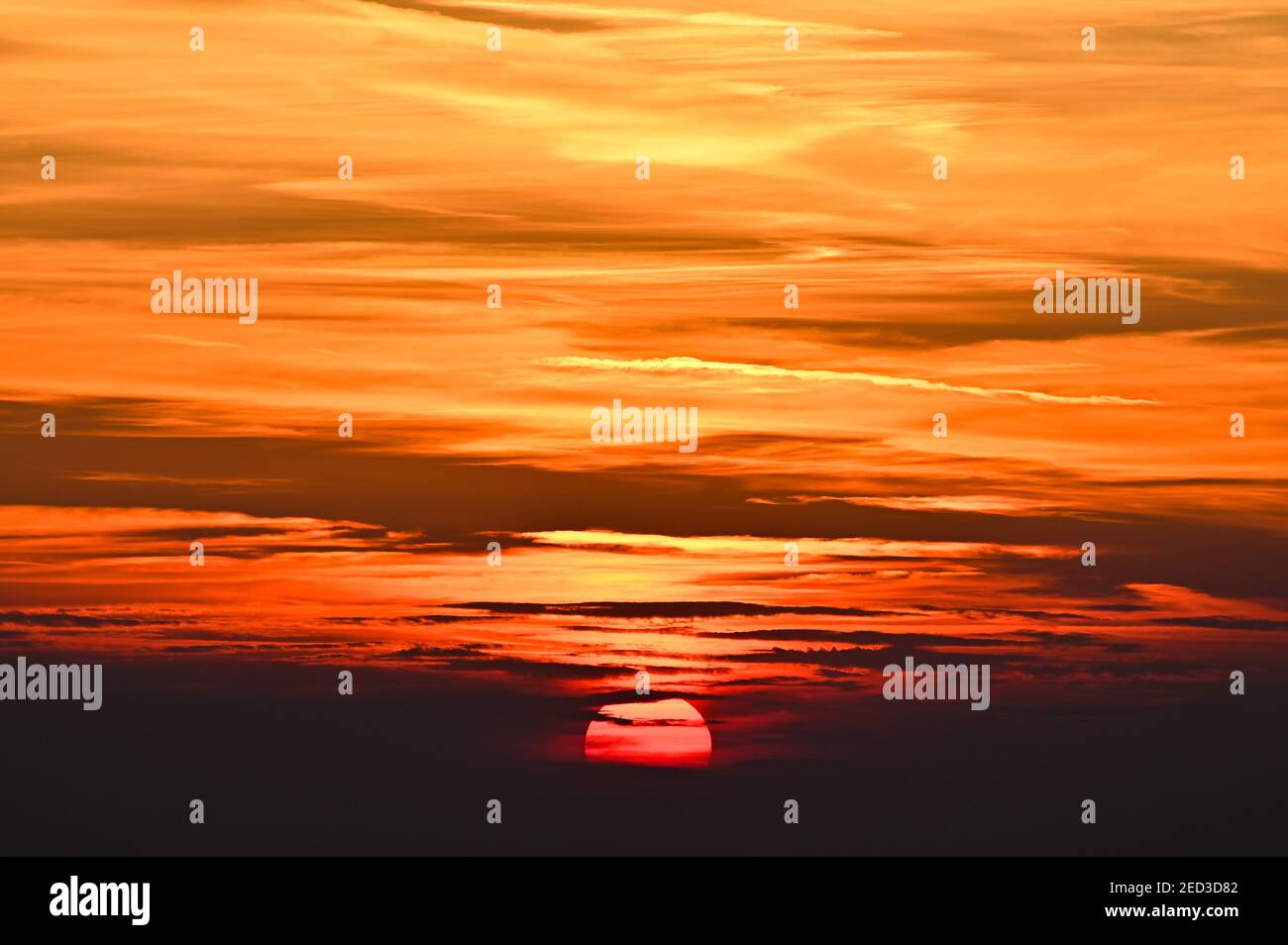 Un gros plan du soleil couchant en partie derrière les nuages Banque D'Images
