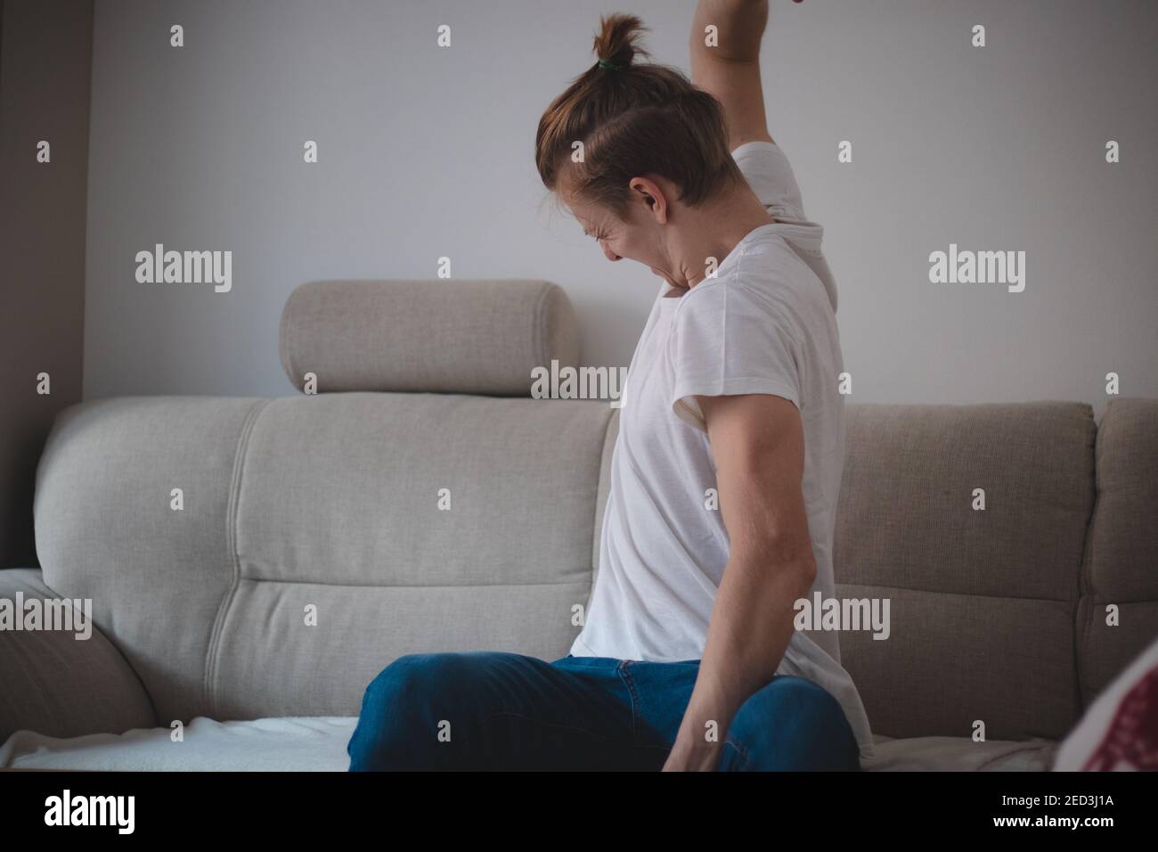 Un joueur en colère de descendance européenne lance ses mains et lance la manette pour une partie perdue. Un homme d'âge moyen dans un T-shirt blanc et bleu jea Banque D'Images