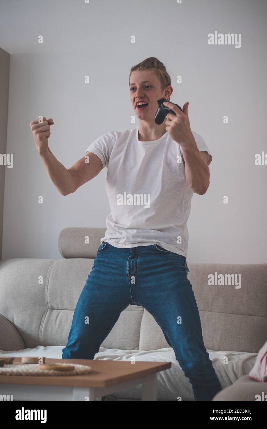 Un jeune joueur en T-shirt blanc se réjouit de gagner du hockey sur glace sur une console de jeux. Lecteur e-sport professionnel. Se réjouir d'une mission réussie. Joyf Banque D'Images