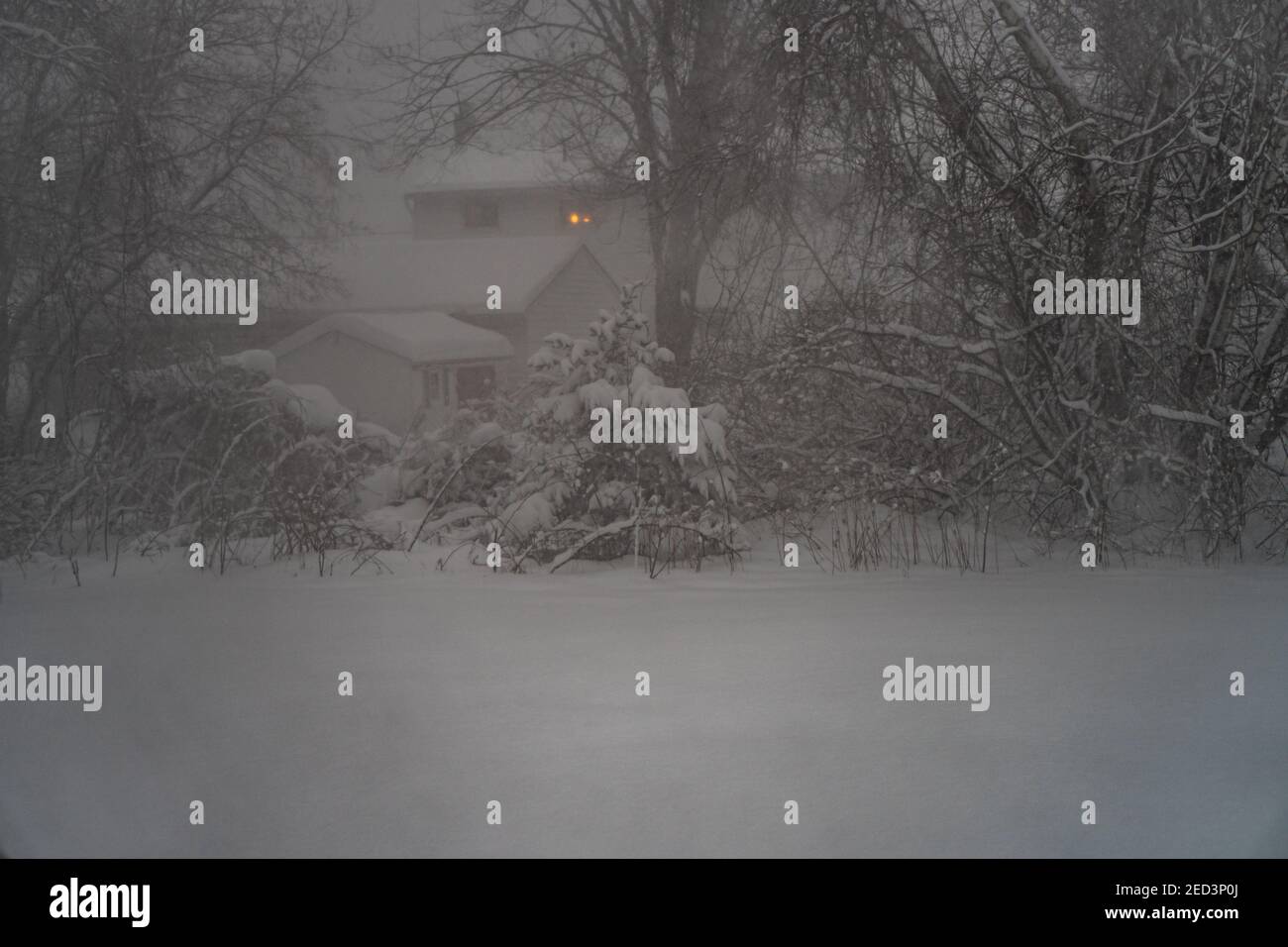 une lumière dans une fenêtre pendant une nuit sombre hiver tempête de neige Banque D'Images