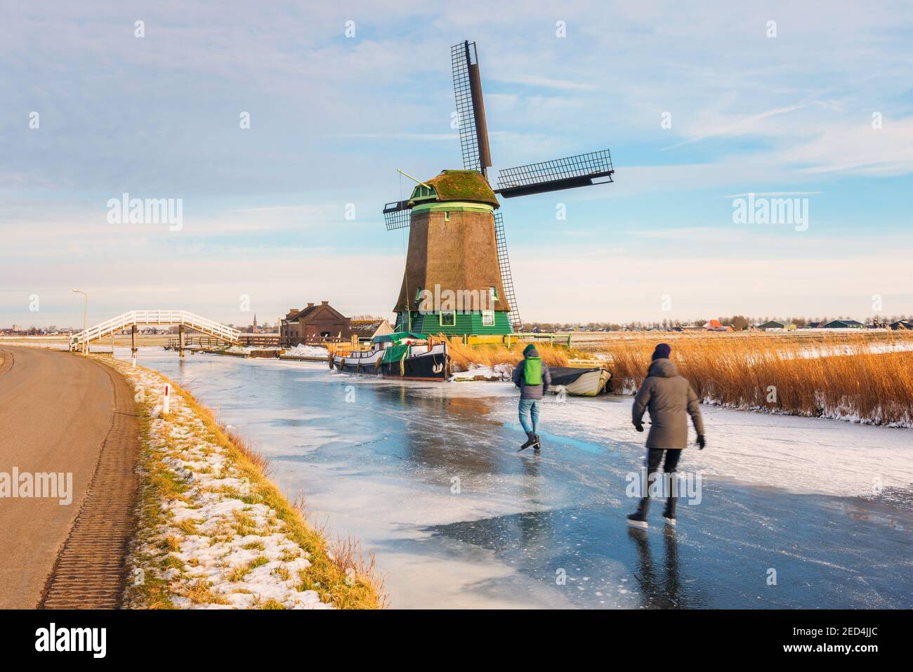 Deux patineurs de glace patinant sur un fossé de polder gelé à Opmeer, pays-Bas, le jour froid de février 2021 Banque D'Images