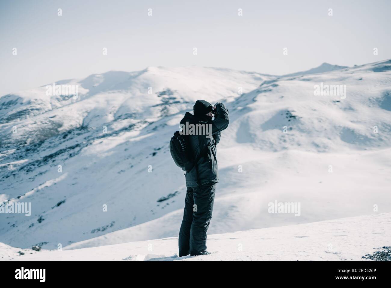 Photographe d'aventure prenant une photo sur une montagne enneigée. Banque D'Images