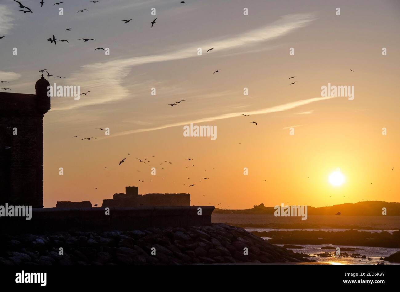 Oiseaux sur un ciel clair au coucher du soleil près du château local Banque D'Images