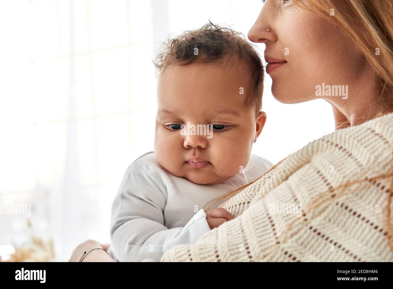 Amour de la mère caucasienne embrassant mignon bébé afro-américain fille bébé. Banque D'Images
