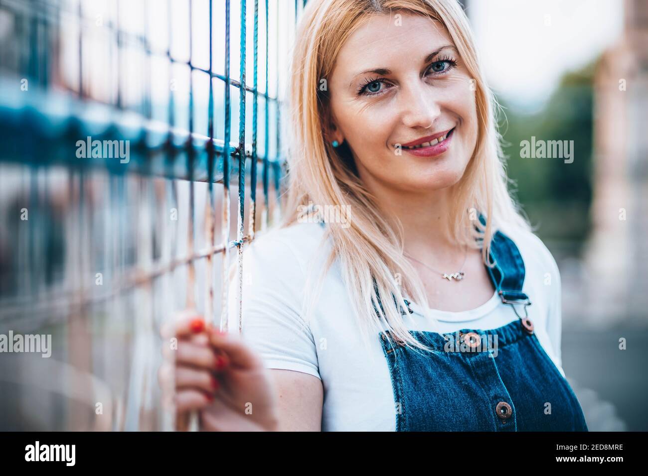 Portrait d'une femme blonde aux yeux bleus avec un Jean et des bretelles Banque D'Images