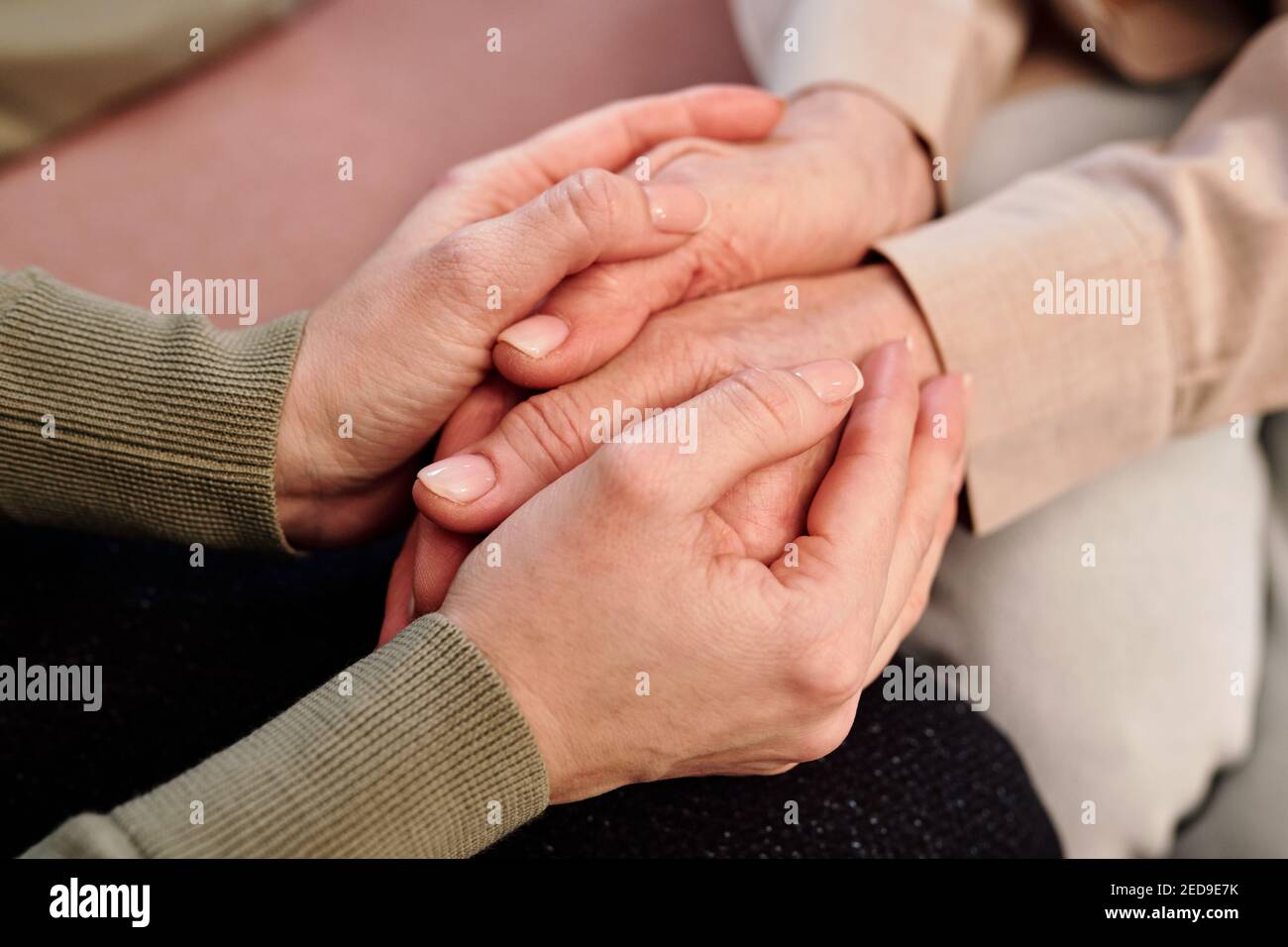 Mains de jeunes femmes de soutien conseiller tenant ceux de maturité femme assis à côté d'elle et réconfortant elle problème Banque D'Images